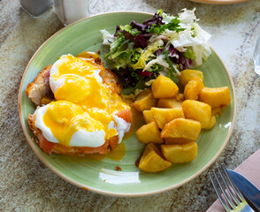 Delicious nutritious American style brunch dish with Eggs Benedict, smoked salmon, fried potatoes...
