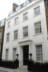 Elegant white townhouse in a London neighborhood showcases classic architectural design with tall windows and decorative railings in a charming residential area