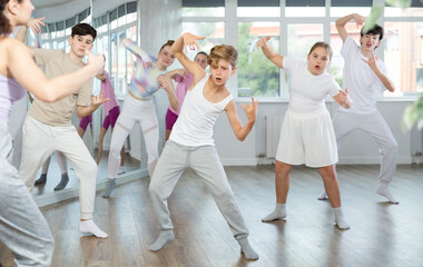 Naklejka premium Young girls and boys repeat the movements of dance teacher, training in a spacious studio