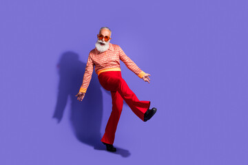 Stylish elderly man dancing joyfully in a retro outfit with a vibrant background, embracing vintage fashion and cheerful vibes