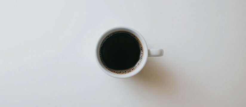 A minimalist top-down view of a white coffee mug filled with dark coffee