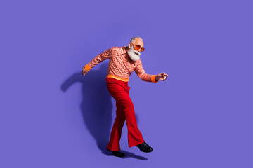 Stylish older man in 70s inspired fashion dancing on vibrant purple background showcasing retro flair and vintage charm