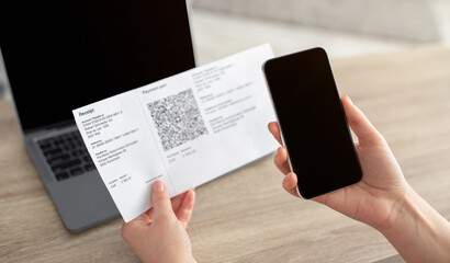 Woman using mobile phone to scan the QR code for the bill through the app, smartphone with blank screen. Paying online from home. Stay safe and have social distance