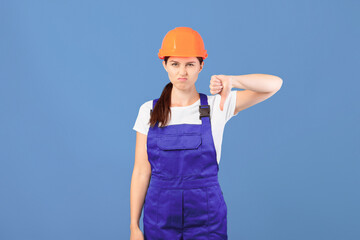 Portrait Of Young Handywoman Lady In Hardhat And Coveralls Showing Thumb Down, Displeased Female...