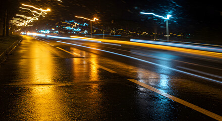 Fototapeta premium Vibrant Cityscape Lights Streaking Across Wet Asphalt Nightscape