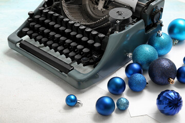 Vintage typewriter with Christmas balls on light blue background