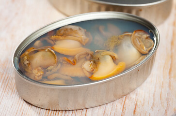 Marinated shellfish in an open tin can on wooden table. High quality photo