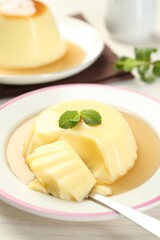 Delicious pudding with caramel sauce and mint served on white table, closeup