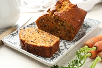 Homemade carrot cake with nuts and vegetables on white wooden table, closeup