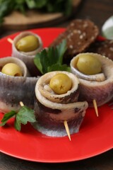 Delicious herring rolls with olives, parsley and bread on table, closeup