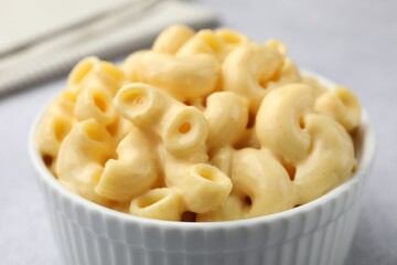 Delicious pasta with cheese sauce in bowl on table, closeup