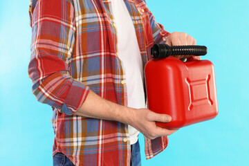 Man holding plastic canister on light blue background, closeup