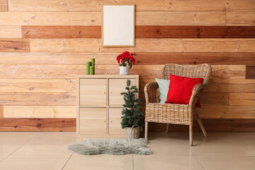 Interior of living room with armchair, fir tree and Christmas plant poinsettia on commode