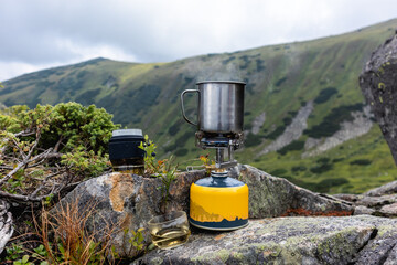 Mountain Tea Brewing Moment. A close-up of a travel tea set with a glass infuser cup and portable...