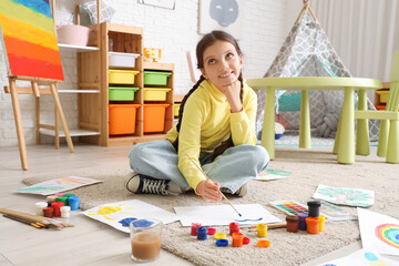 Cute girl painting on carpet at home
