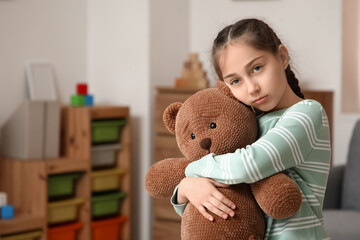 Sad girl hugging toy bear at orphanage