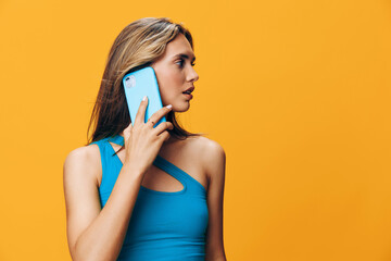 Vibrant image of a stylish woman in blue dress talking on cell phone against bright orange background