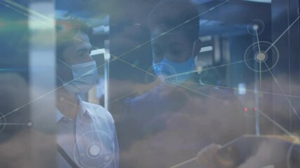 health technology team wearing masks reviewing data in office, with network overlay - Powered by Adobe