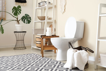 Interior of restroom with toilet bowl, table and shelf unit