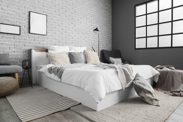 Interior of bedroom with big bed, armchair and lamps