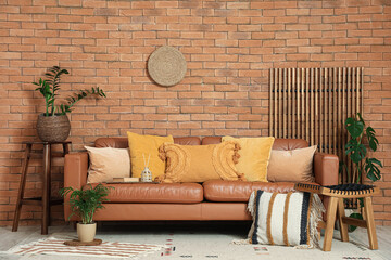 Cozy sofa, stool with cushion and houseplants in interior of living room