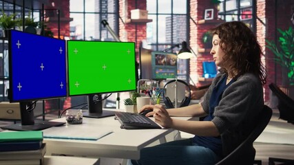 Professional woman works at modern workspace using green screen on dual monitors setup. High tech office environment enhances productivity, IT professionals and content creation. Camera A. - Powered by Adobe