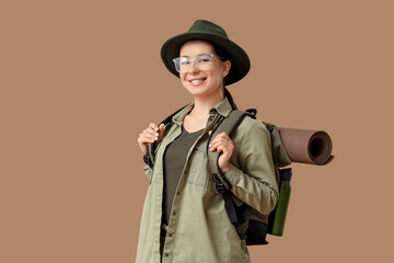 Young female tourist with backpack on beige background