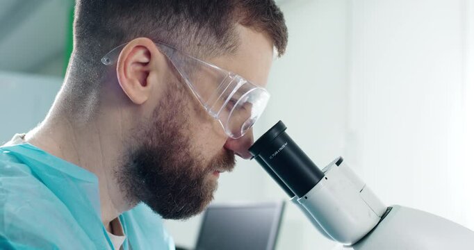  A laboratory technician performs microscope examinations in a modern medical laboratory. The concept of biochemistry and the sciences.                   
