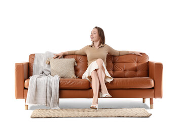 Obraz premium Beautiful young woman sitting on brown sofa against white background