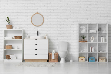 Interior of restroom with toilet bowl, sink and shelf units