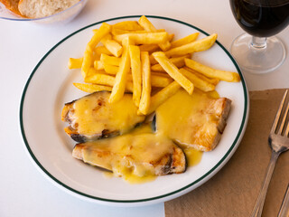Cooked swordfish in hollandaise sauce with french fries closeup