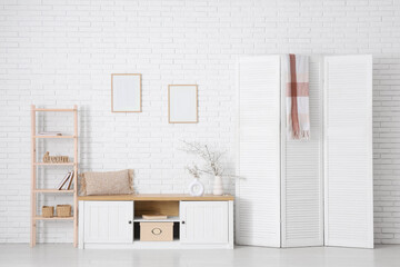 Interior of stylish room with folding screen and blooming tree branches on cabinet