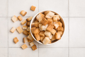 Bowl with crunchy croutons on white tile background