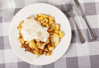 Delicious fried cauliflower with sour cream served on plate