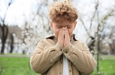 Sick little boy suffering from allergy outdoors