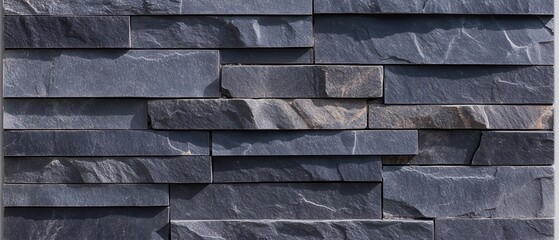 Dark gray stone wall cladding.  Textured rectangular panels in a layered pattern.  Natural stone veneer, a modern design element