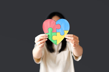 Girl Holding Puzzle Heart on Dark Background