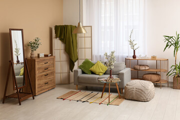 Sofa with folding screen, dressers and vases of white blooming branches near window in living room