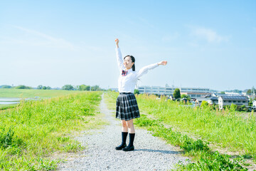 Fototapeta premium 青空の下で両手を上げる女子高生