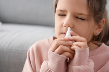 Allergic girl using nasal drops at home, closeup
