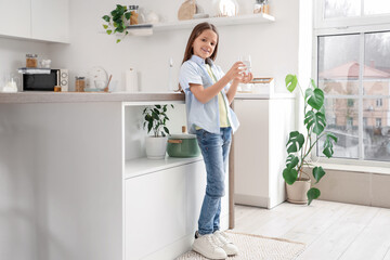 Cute girl with glass of water in kitchen