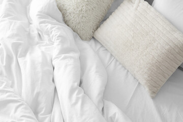 Soft pillows with white blanket on bed, top view