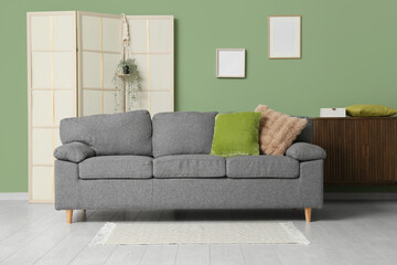 Interior of living room with folding screen, sofa and blank frames