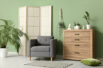 Interior of living room with folding screen, armchair and green plants