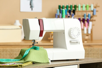Sewing machine with cloth and tape measure on table in atelier, closeup