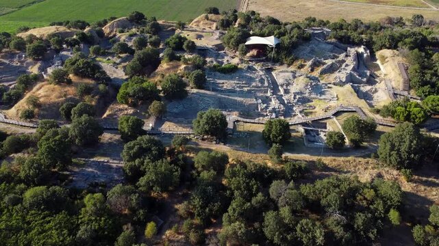 Remains of ancient Troy stone ruins surrounded by grassland near Tevfikiye, Turkey, aerial overview