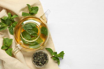 Teapot and mint on light wooden background, top view