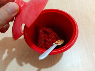 Opening Red Container with Paste and Spoon on Table