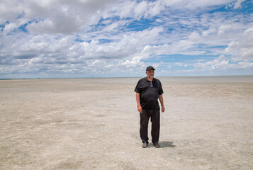 desertification effects of climate change on former agricultural fields, sand and desert with blue sky, man standing