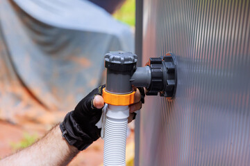 Fototapeta na wymiar Worker is attaching hose to swimming pump pool system, ensuring secure connections at an outdoor work site